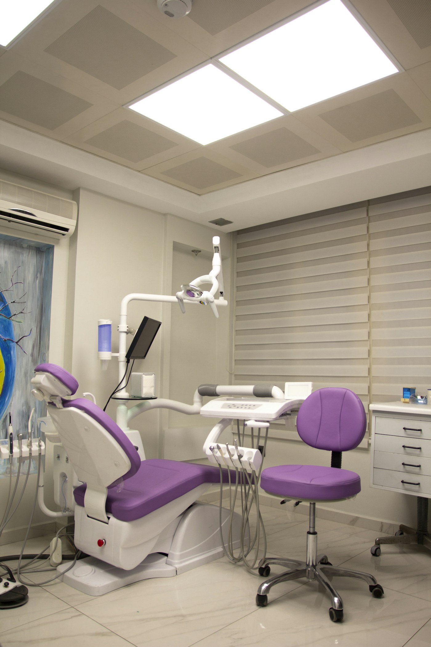 Mor tedavi koltuğu ve beyaz dolapları bulunan diş kliniği