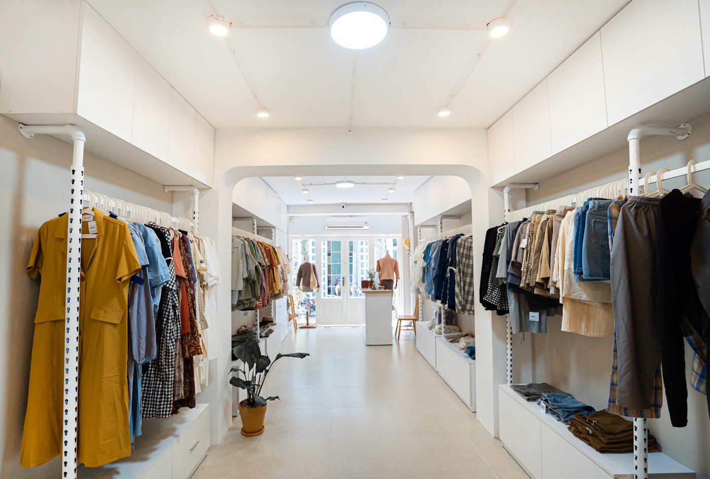 Beyaz raflar ve kıyafet askıları bulunan butik mağaza
